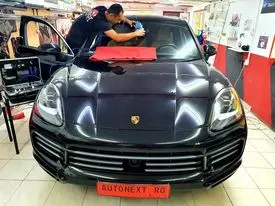 Tehnician reparând o ciobitură în parbrizul unui Porsche Cayenne, în atelier
